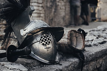 A medieval armor helmet, sword, and glove against a stone wall depicting historical combat gear. HD wallpaper