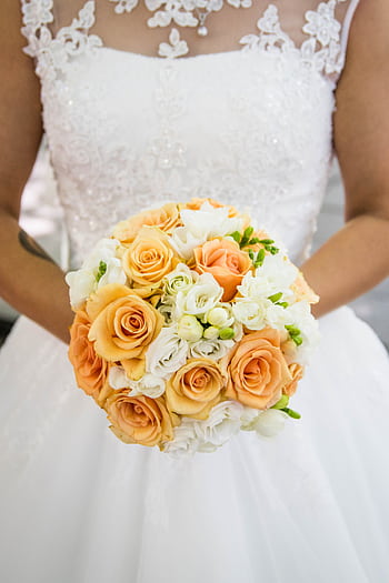A bride holding an elegant bouquet of peach and white roses, ready for the wedding ceremony. HD phone wallpaper