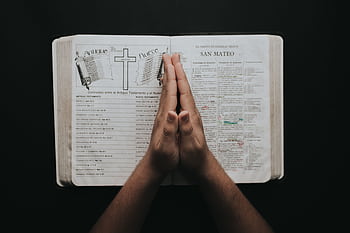 Hands clasped in prayer on an open Bible showing the book of Matthew, emphasizing faith and spirituality. HD wallpaper