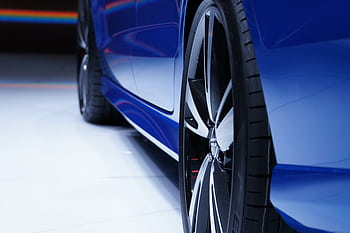 Close-up shot of a blue car highlighting the stylish alloy wheel. Perfect for automotive enthusiasts. HD wallpaper