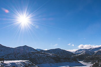 A stunning winter mountain landscape with a bright sun and clear blue sky. HD wallpaper