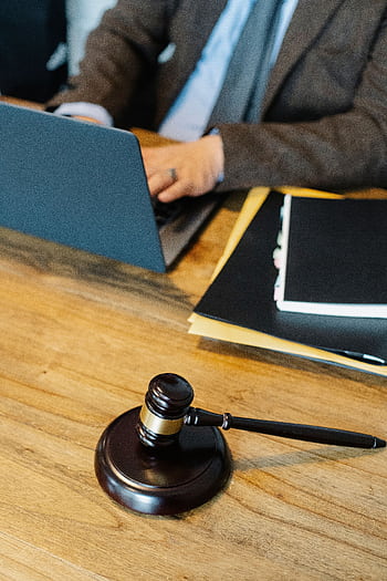 Legal professional working on a laptop with gavel on wooden desk. HD phone wallpaper