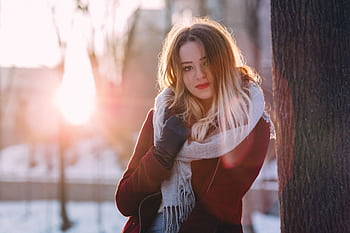 A woman in a cozy scarf enjoying a winter day with sunlight streaming through the trees. HD wallpaper