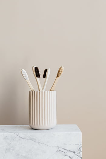 Minimalist bamboo toothbrushes in a ceramic holder for eco-friendly oral care. HD phone wallpaper