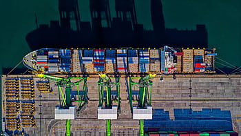 High angle aerial view of a cargo ship at a bustling port in Jakarta, showcasing global trade. HD wallpaper