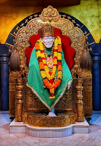 A vibrant close-up of Sai Baba statue adorned with flowers and intricate decorations. HD phone wallpaper