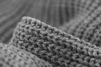 Macro black and white showcasing the intricate texture of grey knitted wool fabric. HD wallpaper