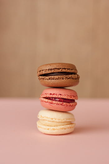 Three assorted macarons stacked in bright pastel colors against a plain background. HD phone wallpaper