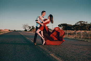 A couple in a passionate dance pose on an empty highway at sunset, showcasing love and romance. HD wallpaper