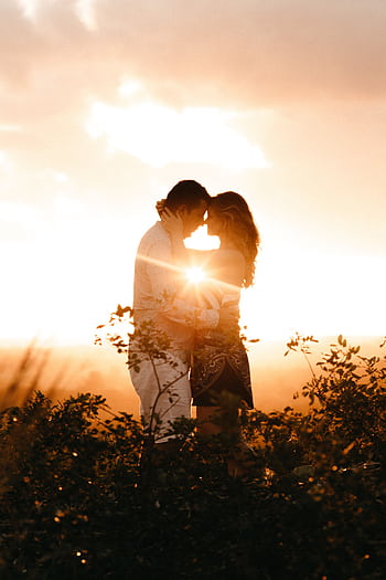 A romantic couple embraces in a sunlit outdoor setting, capturing love and warmth. HD phone wallpaper