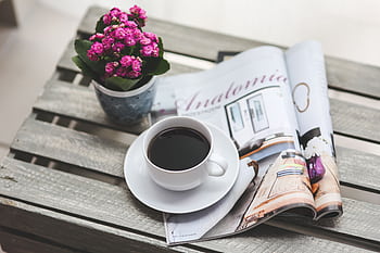 A relaxing scene of a coffee cup, pink flowers, and a magazine on a wooden table. HD wallpaper