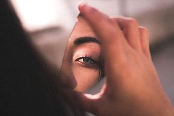 A captivating of a woman's eye reflected in a broken mirror piece with soft lighting. HD wallpaper