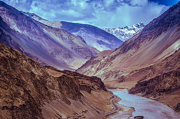 Majestic view of a Himalayan valley with winding river beneath dramatic clouds. HD wallpaper