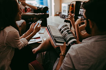 Casual group discussion with people reading a magazine and interacting indoors. HD wallpaper