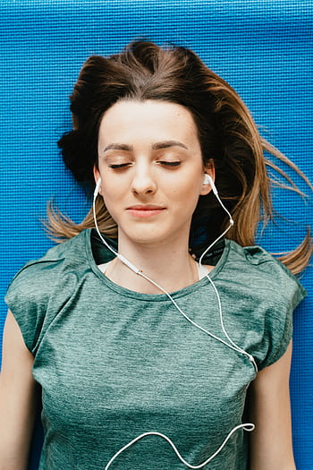 Young woman lying on yoga mat with ears, eyes closed in relaxation. HD phone wallpaper