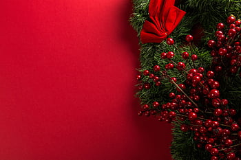 A vibrant Christmas wreath with red berries and bow on a red background. HD wallpaper