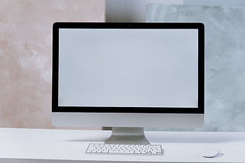 A sleek iMac computer on a minimalist white desk with a keyboard and mouse. HD wallpaper