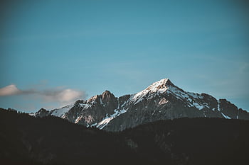 Stunning view of snow-capped mountains against a blue sky, perfect for nature lovers. HD wallpaper