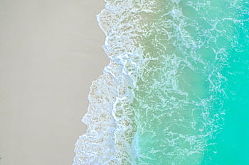 Serene aerial shot of turquoise waves gently caressing the sandy shore, capturing nature's beauty. HD wallpaper