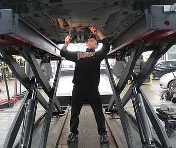 Mechanic inspecting and repairing a vehicle in a professional auto garage. HD wallpaper