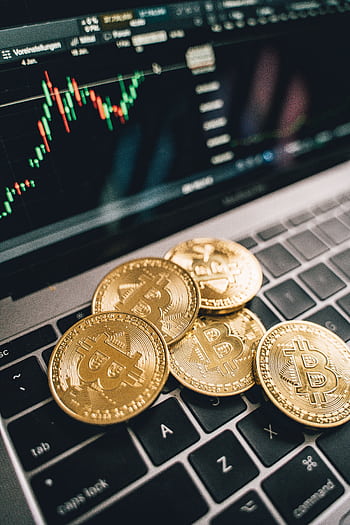 Close-up of gold Bitcoin coins on a laptop keyboard with a stock chart, symbolizing cryptocurrency market analysis. HD phone wallpaper