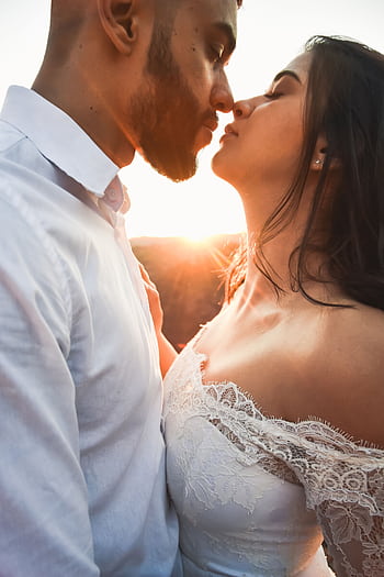 A couple embraces passionately at sunset, capturing love and intimacy outdoors. HD phone wallpaper