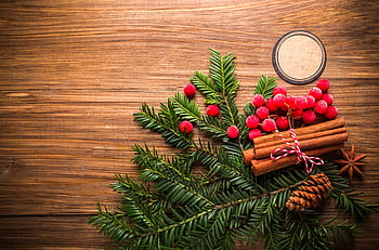 Warm holiday-themed flat lay with festive decorations including pine cones and berries on wooden background. HD wallpaper