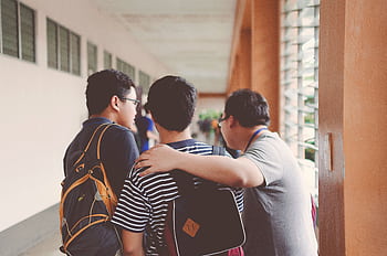 Group of male teenagers walking in a school corridor with backpacks, bonding and chatting. HD wallpaper