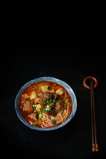 Close-up of a flavorful beef ramen noodle dish with chopsticks on a dark background. HD phone wallpaper