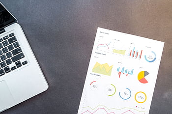 Modern desk setup with a laptop and analytical charts showcasing data interpretation and business analysis. HD wallpaper