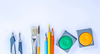 A vibrant collection of art supplies including brushes, pencils, and paints on a white background. HD wallpaper