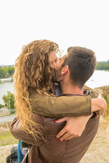 A loving couple shares an intimate moment with a scenic river view. HD phone wallpaper