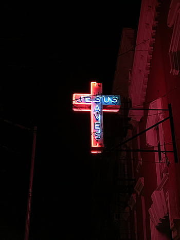 A glowing neon cross sign that reads 'Jesus Saves' against a dark night sky. HD phone wallpaper