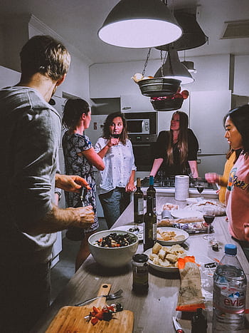 A group of adults enjoying a casual dinner party in a cozy, modern kitchen setting. HD phone wallpaper