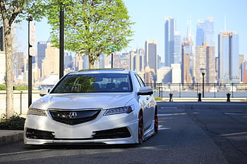 A customized silver Acura parked with a city skyline backdrop, showcasing urban car culture. HD wallpaper