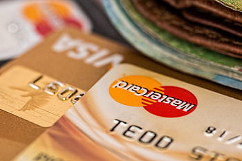 Macro shot of credit cards showing Visa and Mastercard logos next to a wallet, ideal for finance themes. HD wallpaper