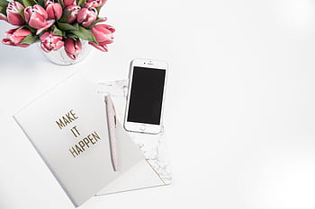 A minimalist desk setup featuring a smart, pink tulips, and a motivational notepad. HD wallpaper