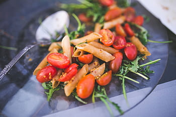 Fresh penne pasta salad with cherry tomatoes and arugula on a glass plate. HD wallpaper