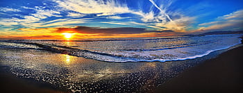 Breathtaking view of a vibrant sunset over the ocean waves with a sandy beach in the foreground. HD wallpaper