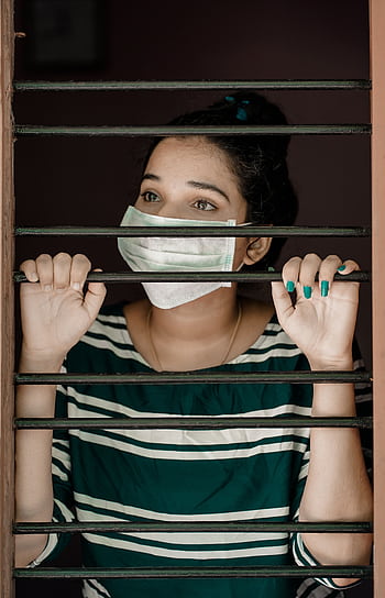 A woman wearing a face mask looks through window bars during COVID-19 lockdown. HD phone wallpaper