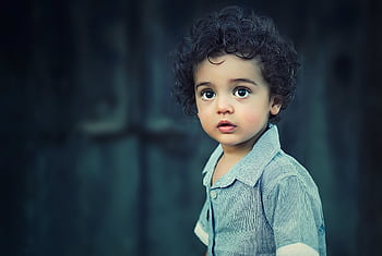 Charming portrait of a young boy with curly hair and striking eyes. HD wallpaper