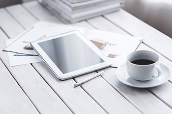 White tablet with stylus and coffee cup on modern office desk setup. HD wallpaper