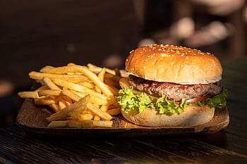 Close-up of a tasty cheeseburger and crispy french fries on a wooden platter. HD wallpaper
