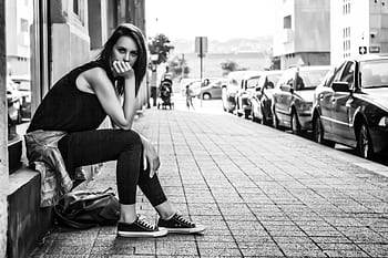 Black and white of a woman posing on a city sidewalk, expressing modern fashion. HD wallpaper