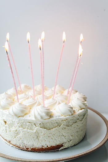 A white frosted birtay cake with lit candles on a ceramic plate, perfect for celebrations. HD phone wallpaper