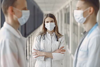 Medical professionals wearing face masks in a hospital hallway. HD wallpaper