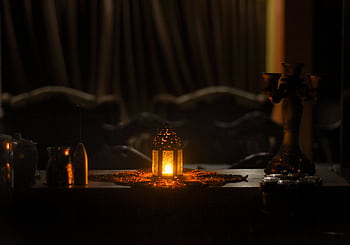 A beautifully lit lantern on a decorated table in a dimly lit room, evoking a sense of warmth and tradition. HD wallpaper
