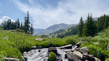 Scenery Nature Background Green Trees Bushes Mountains Stones Rocks Water Stream During Daytime Under White Clouds Blue Sky Nature HD wallpaper