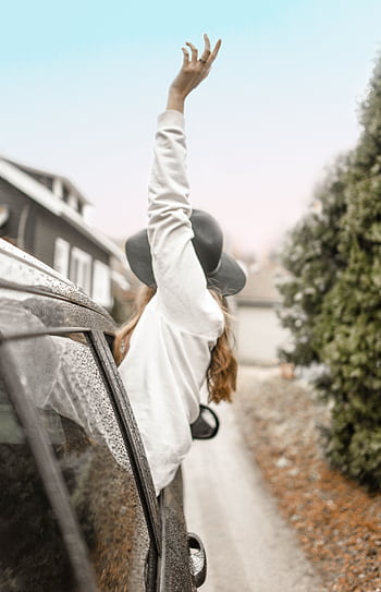 Care woman enjoying a rainy road trip, hand outstretched from car window. HD phone wallpaper