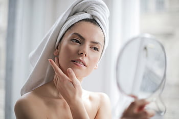 A serene and elegant woman enjoys a skincare ritual, enhancing her natural beauty in the comfort of her home. HD wallpaper